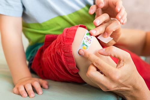 Kind bekommt ein Pflaster auf das Knie